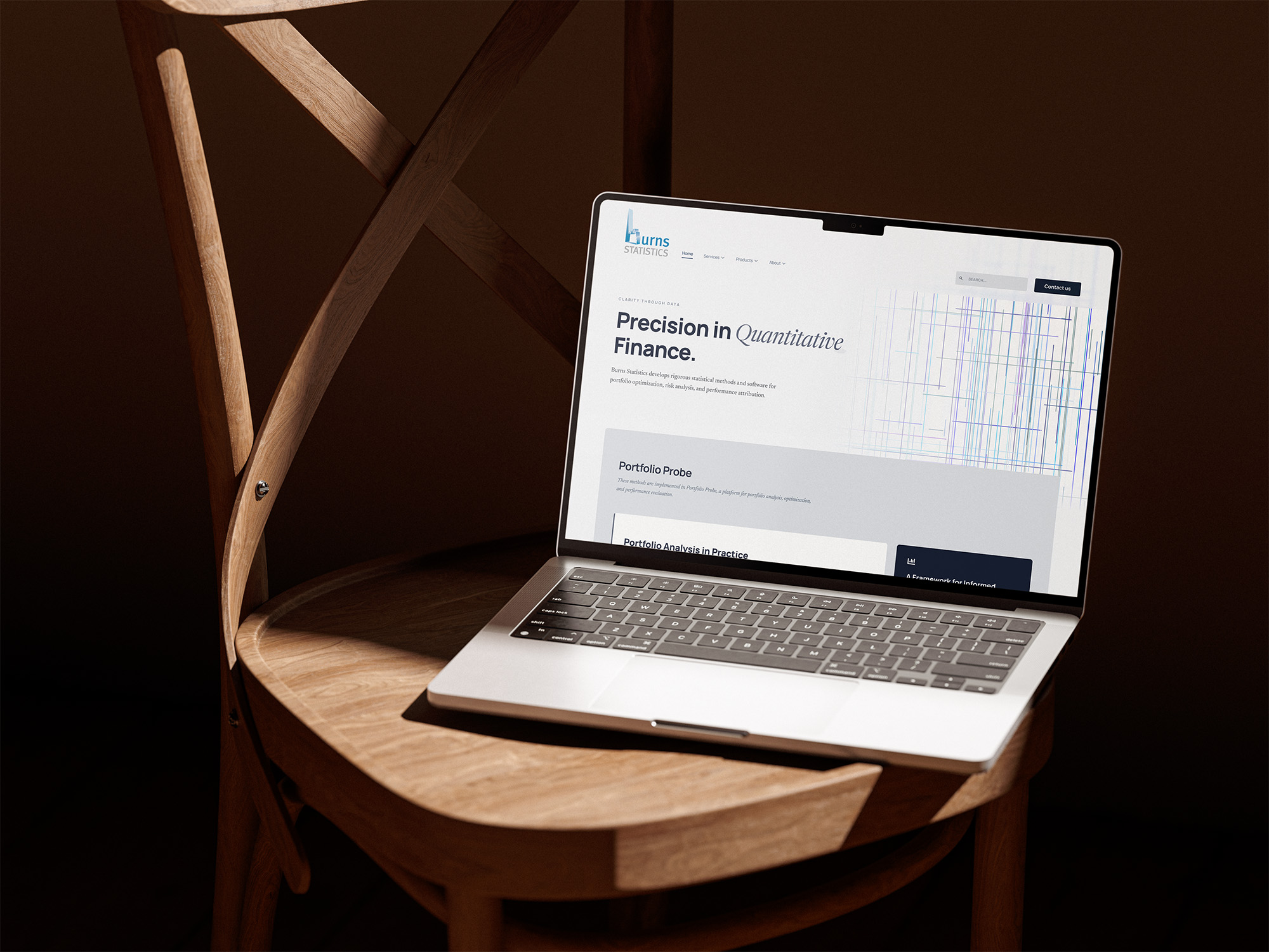 En laptop som står på en stol i ett dunkelt rum. På skärmen visas hemsidedesignen för Burns statistics.