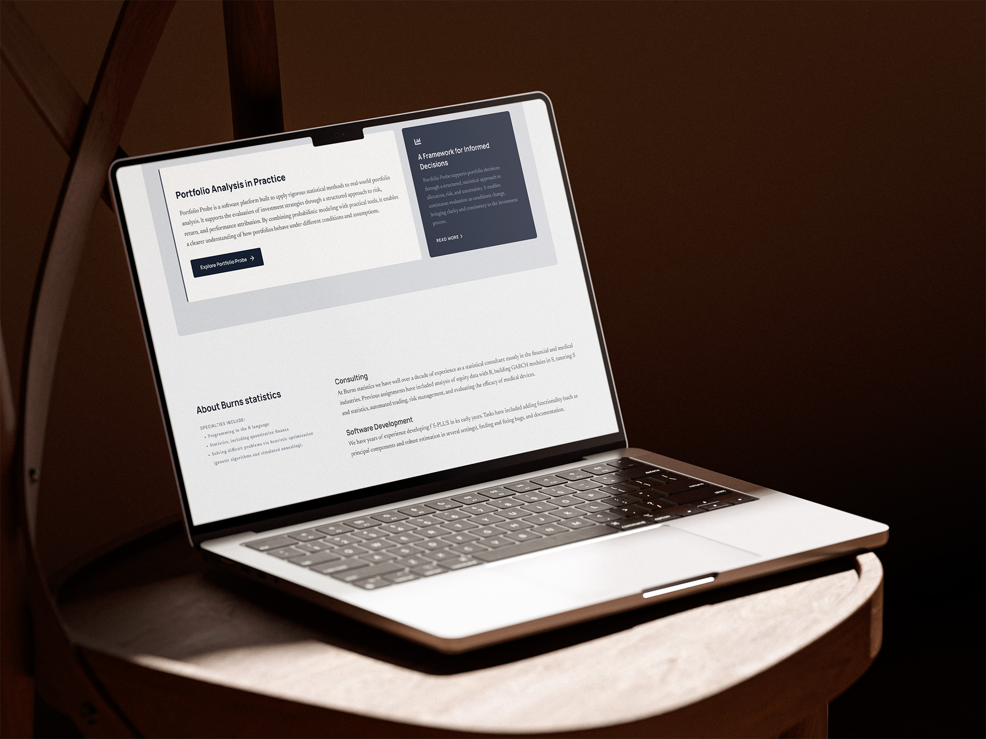 En laptop som står på en stol i ett dunkelt rum. På skärmen visas hemsidedesignen för Burns statistics.